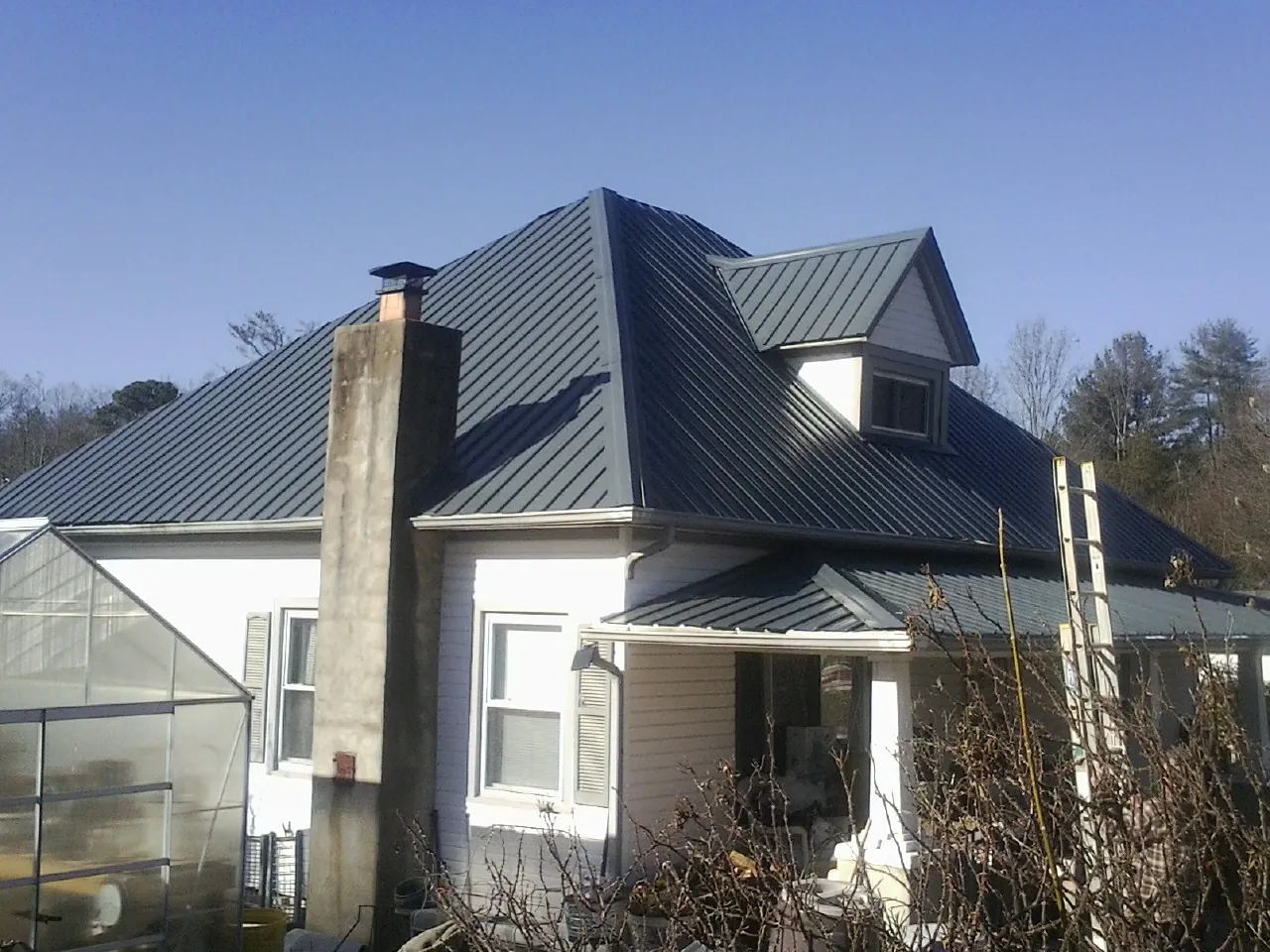 Dark blue standing seam metal roof on a white farmhouse with dormer — Slate & Tile Roof Repair by Roofing Brothers in Rohnert Park