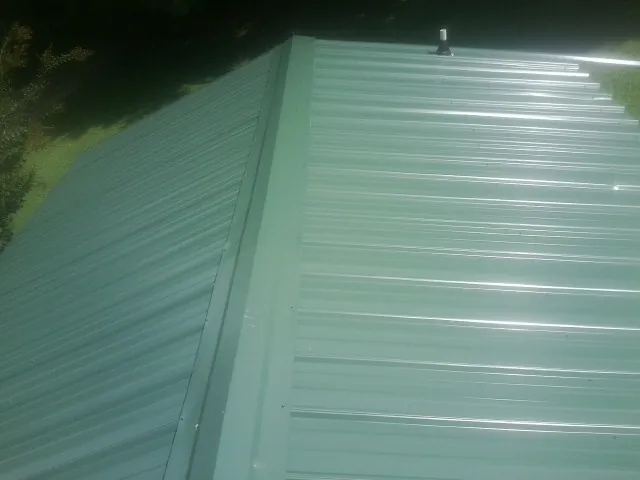 New green metal panels meeting at the ridge of a roof — Flat Roof Repair work by our crew in Rohnert Park