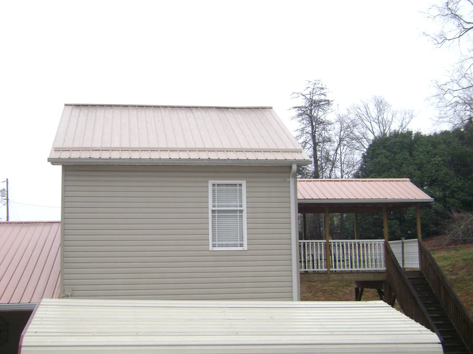 Tan metal roofs on a two story addition and attached porch, from a Roof Replacement job in Rohnert Park