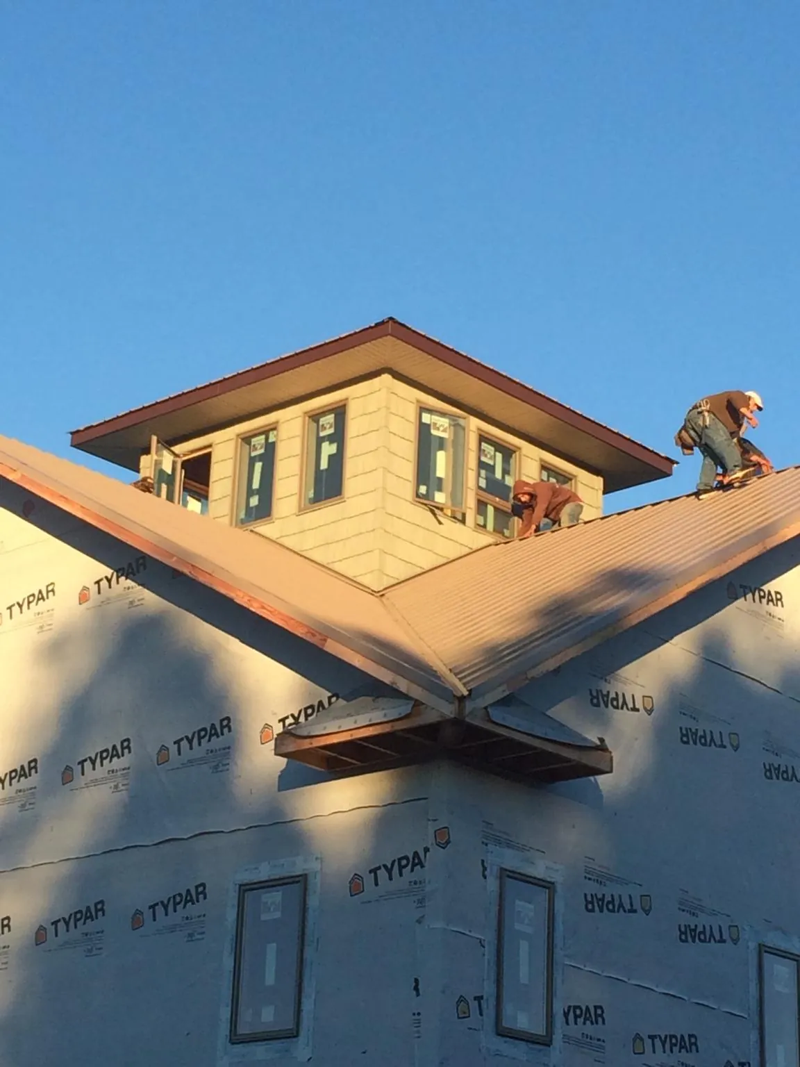 Roofers working around a rooftop cupola on a new metal roof at sunset — Roof Waterproofing in Rohnert Park by Roofing Brothers